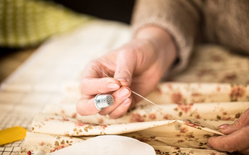 Close-up partial view of woman sewing cloth with needle and thread